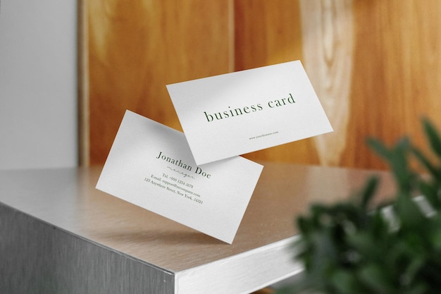 Clean minimal business card mockup floating on table with leaves background psd file