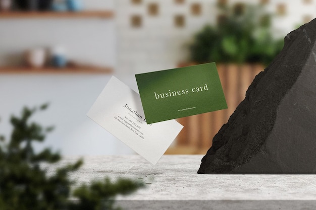 Clean minimal business card mockup floating on top table with black stone and plant