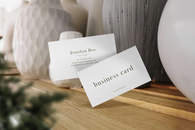 Clean minimal business card mockup floating on vase shelf with plant background PSD file
