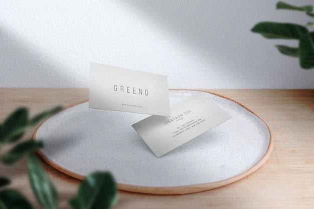 Чистый минимальный макет визитки на белой тарелке с листьями