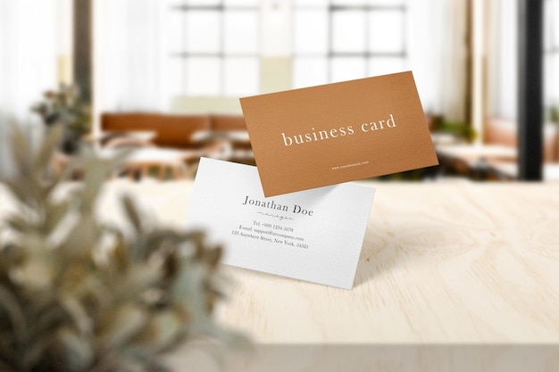 Clean minimal business card mockup on top table in cafe with leaves