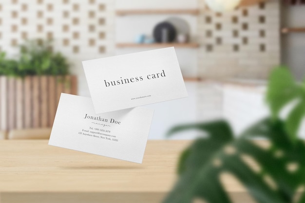 Clean minimal business card mockup on top table in soft cafe with leaves