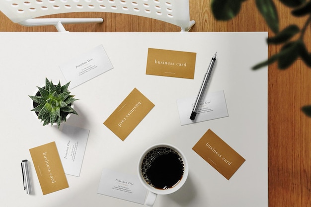 Clean minimal business card mockup on top table with coffee cup and plant background. PSD file.