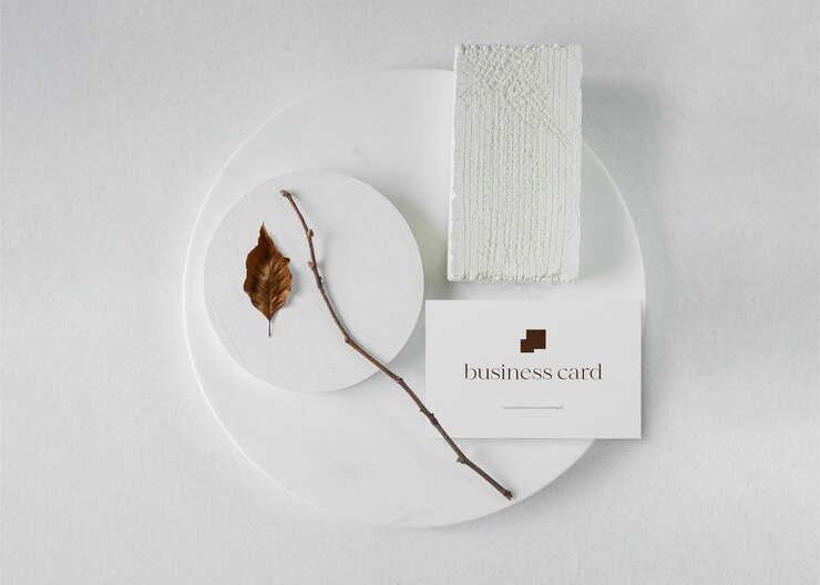 PSD clean minimal business card mockup on white stone plate with dried leaf background