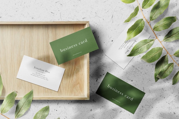 Clean minimal business card mockup on wooden plate with leaves