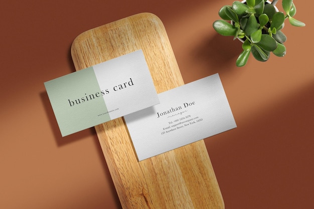 Clean minimal business card mockup on wooden plate with plant