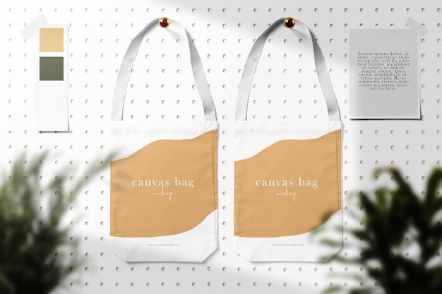 Clean minimal canvas bag mockup on wallpaper background with papers pins tape and plants foreground