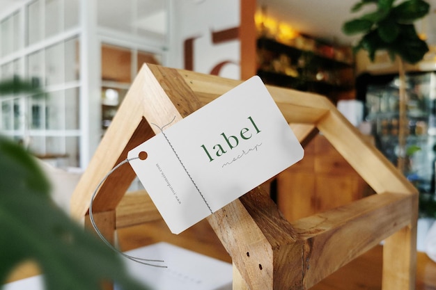 Mockup di etichetta minimale pulito che galleggia su struttura in legno con sfondo di foglie. file psd.
