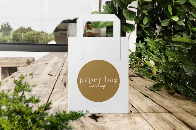 Clean minimal paper bag mockup on cafe background with plant foreground