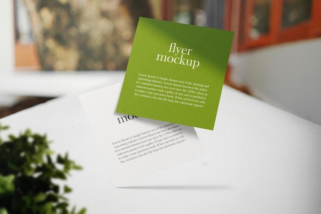 Clean minimal square flyer mockup on cafe background with plant foreground