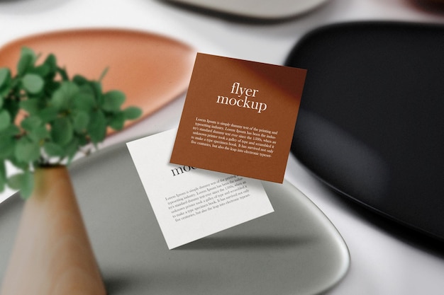 Clean minimal square flyer mockup floating on plates with plant. psd file.