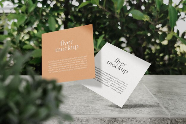 Clean minimal square flyer mockup floating on top granite bench with leaves psd file