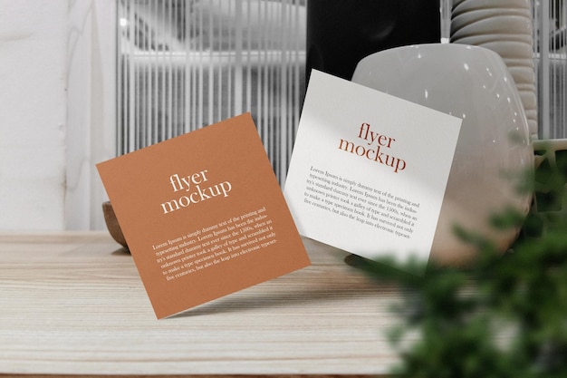 Clean minimal square flyer mockup floating on wooden table with plant PSD file