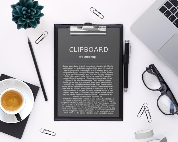 Clipboard with a cup of coffee and a laptop on a desk mockup PSD