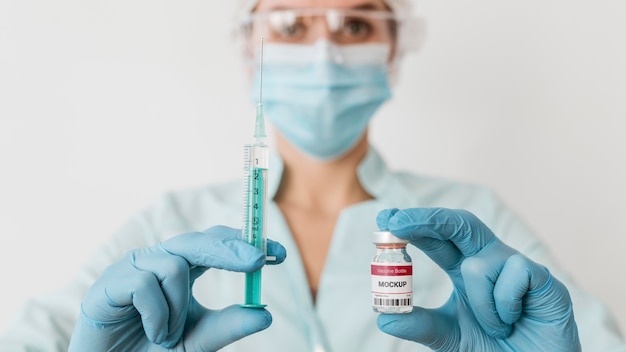 close up doctor with mask holding vaccine vial