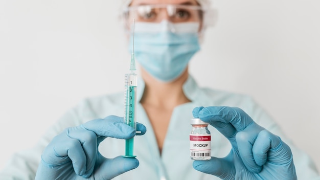 Close up doctor with mask holding vaccine vial