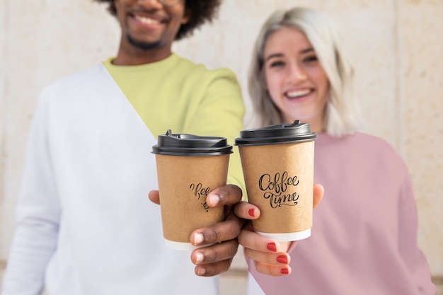 Amici del primo piano con felpe con cappuccio e tazza di caffè