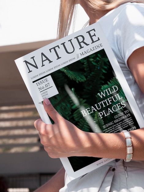 PSD close-up hand holding a nature magazine mock up