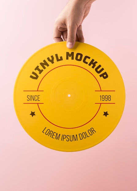 Chiuda sulla mano che tiene il mockup in vinile giallo