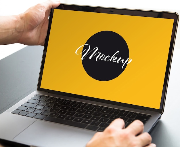 Chiuda in sulle mani che aprono il mockup del laptop