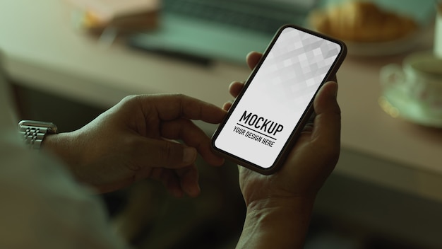 Close-up van mannenhand met behulp van smartphone zittend op de werkplek