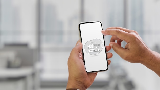 Close up view of hands using mock up smartphone on blurred indoor background