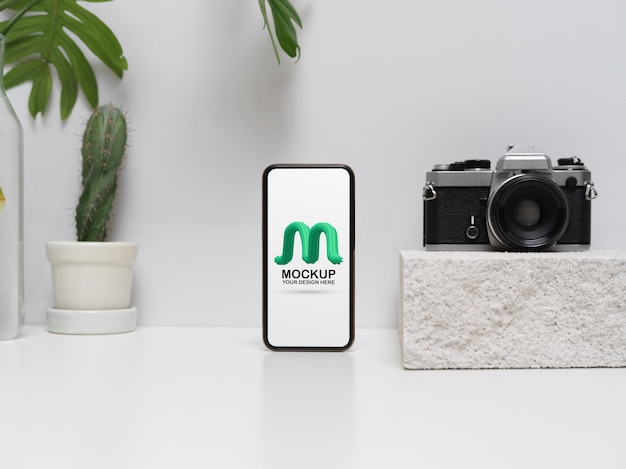 Vista ravvicinata di mock up smartphone sul tavolo bianco con fotocamera e decorazioni in soggiorno