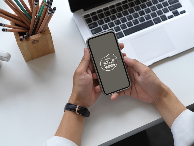 画面のモックアップとスマートフォンを持っている手のビューをクローズアップ