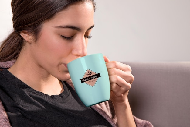 Donna del primo piano che beve dalla tazza blu