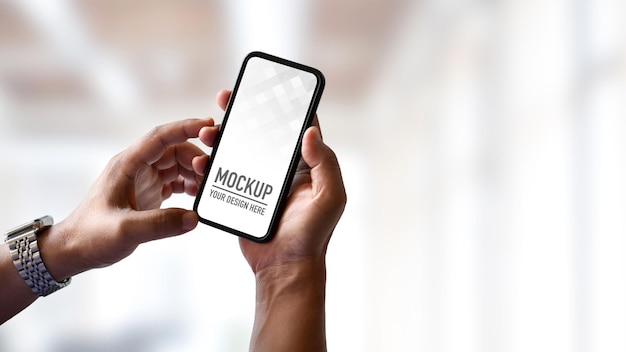 Close up of young man holding mockup smartphone