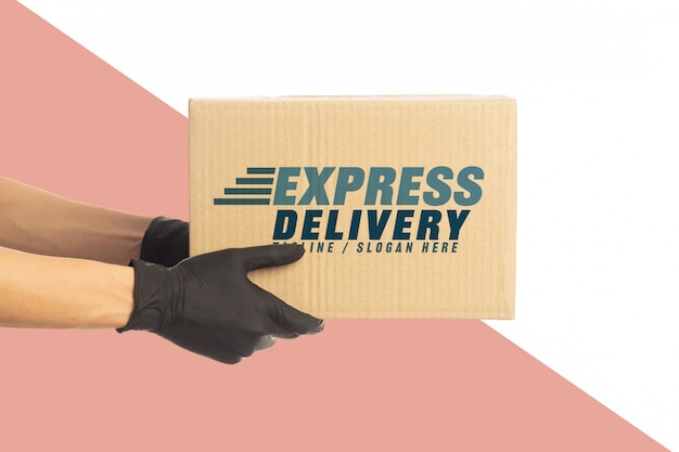 closeup delivery man hand in medical gloves holding cardboard box mockup template.