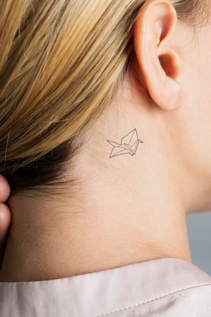 closeup of a simple behind the ear tattoo of a young woman