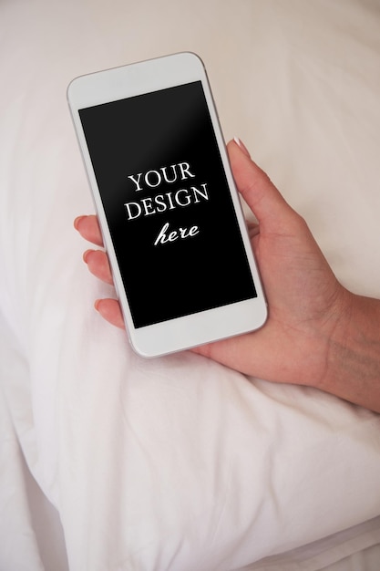 Closeup of a smartphone in a woman's hand on the background of a pillow Mockup