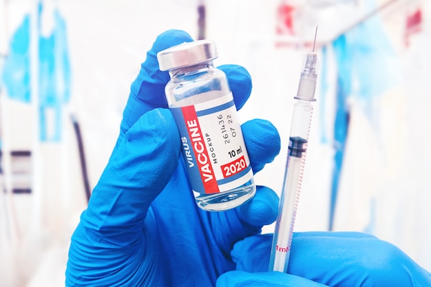 PSD closeup of vaccine bottle with syringe and needle in doctor's hands mockup