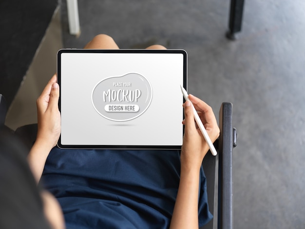 Closeup view of woman using mock up tablet while sitting on a chair on her workspace