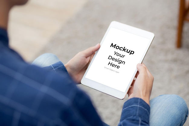 PSD ソファの上の空白の画面を表示するタブレットコンピューターのモックアップを使用してクローズアップ若いアジア人男性