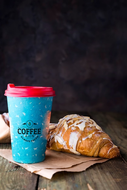 Coffee to go in a paper cup with croissants mockup