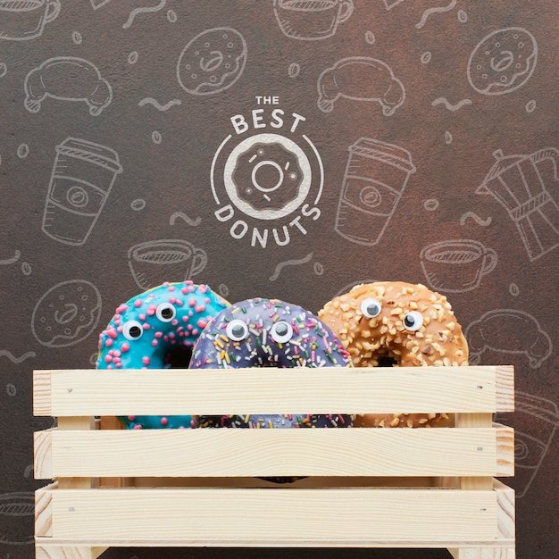 Colorful donuts in wooden crate with mock-up