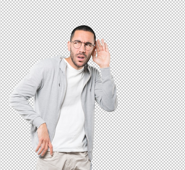 Concentrated young man making a gesture of trying to hear something