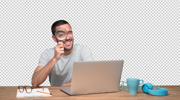 PSD concentrated young man using a magnifying glass on his laptop