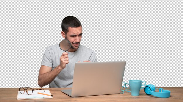 Concentrated young man using a magnifying glass on his laptop