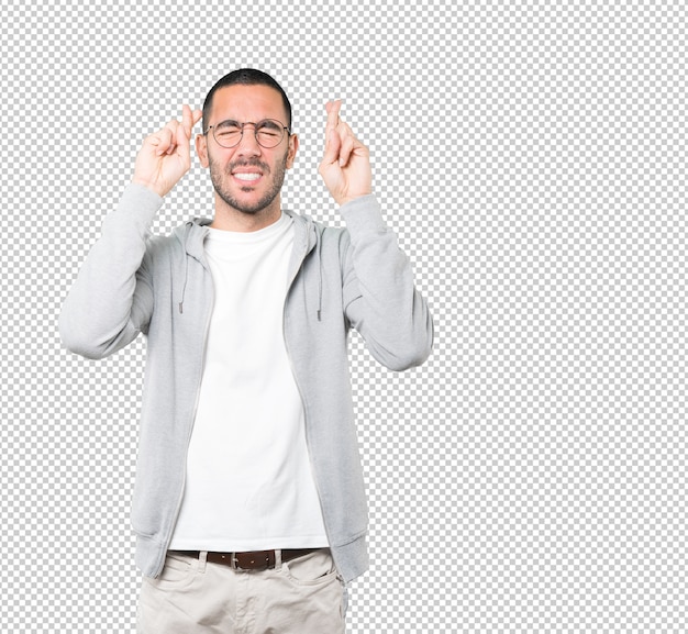 Concerned young man doing a crossed fingers gesture