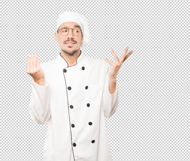 Confused young chef making an italian gesture of not understand