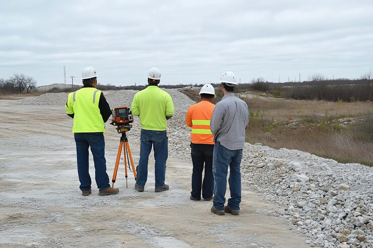 PSD construction workers observing surveying equipment on a road construction site