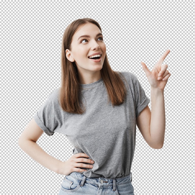 Copy space for advertisement Close up of handsome caucasian young female student with dark hair in casual grey clothes smiling brightfully looking aside with happy expression pointing on white back