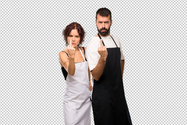 Couple of cooks making horn gesture. negative expression