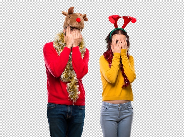 PSD couple dressed up for the christmas holidays covering eyes by hands and looking through the fingers