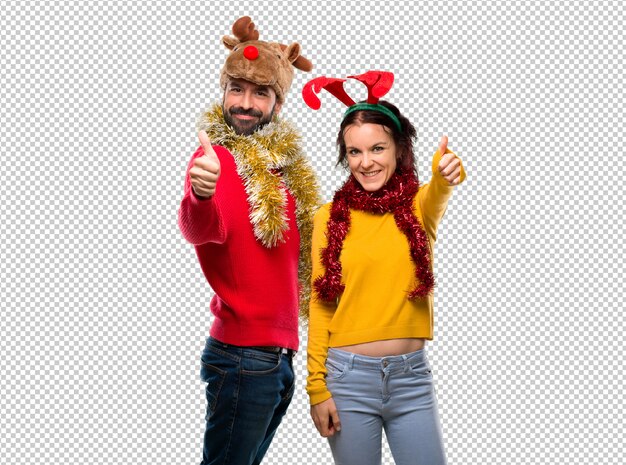 PSD couple dressed up for the christmas holidays giving a thumbs up gesture and smiling