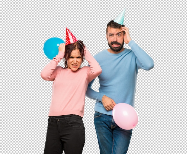 Coppia con palloncini e cappelli di compleanno prende le mani sulla testa perché ha l'emicrania
