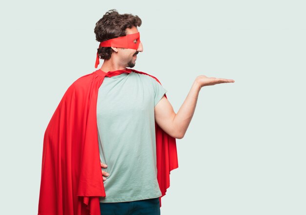 crazy man as a super hero smiling with a satisfied expression showing an object or concept